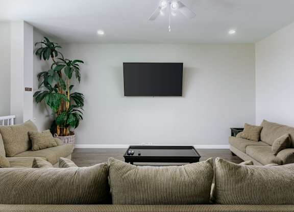 A living room with a large couch and a flat screen TV mounted on the wall.