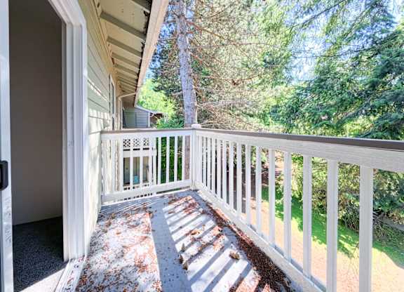A white railing leads to a house with a door open.