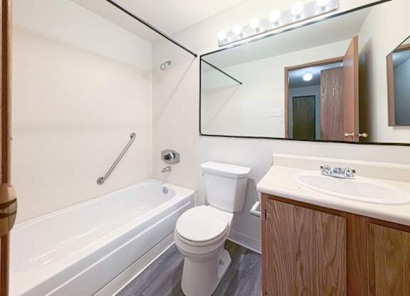 A white toilet sits next to a white bathtub in a bathroom.