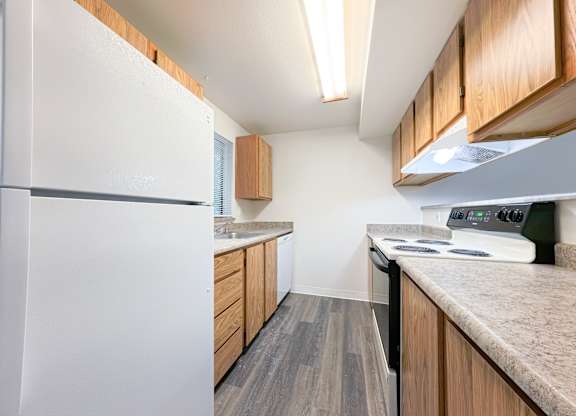 A kitchen with a white fridge, wooden cabinets, and a stove top oven.
