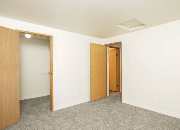 A room with two doors, one open, and carpeted flooring.