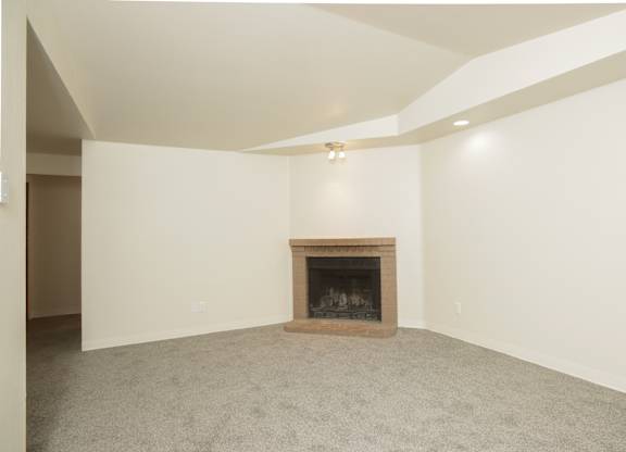 A room with a fireplace and carpeting.