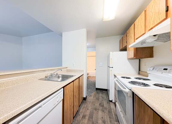 A kitchen with white appliances and wooden cabinets.