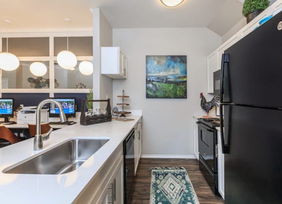 a kitchen with a black refrigerator freezer next to a stove top oven