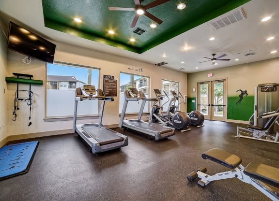 a gym with cardio equipment and a green ceiling