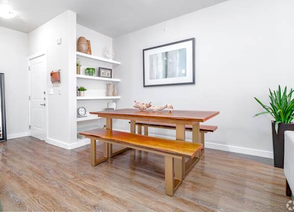 A room with a wooden table and bench, a chair, and a potted plant.