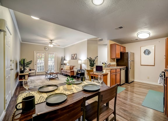 a dining area with a wooden table and chairs and a kitchen in the background