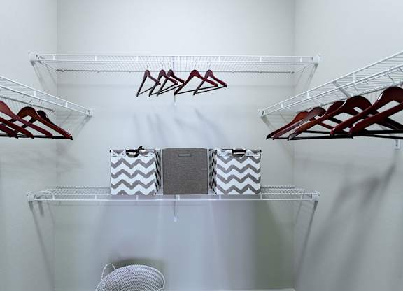 A white closet with clothes hangers and a fan.