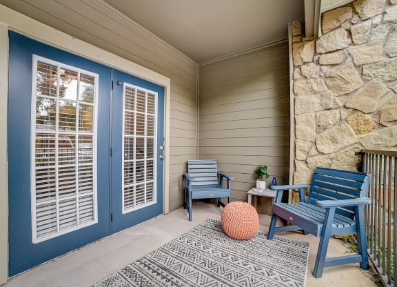front porch with two chairs and a table with a potted plant
