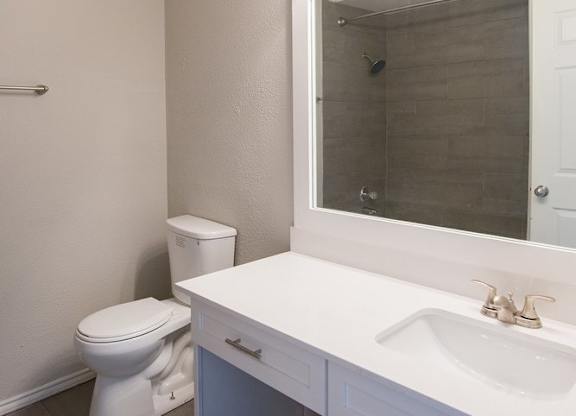 A white bathroom with a toilet, sink and mirror.