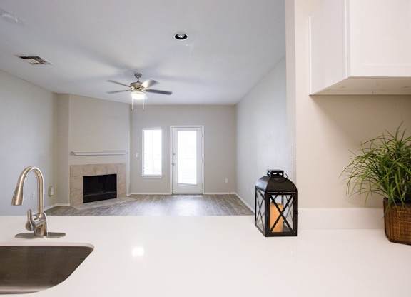 A modern kitchen with a white countertop and a stainless steel sink.