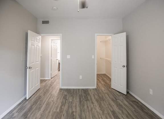 A room with white doors and wood flooring.