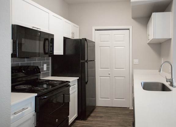 A kitchen with black appliances and white cabinets.