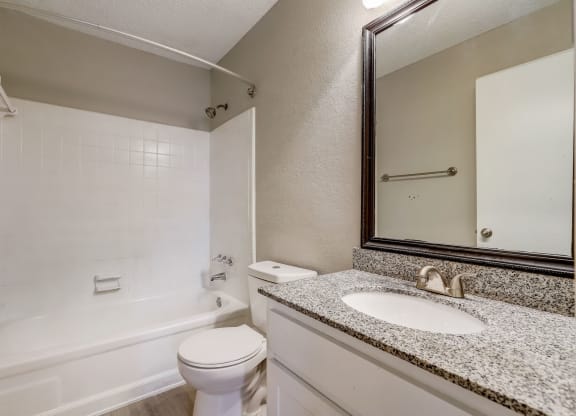 a light colored bathroom with sink and toilet and shower with white tub at Veridian at Sandy Springs