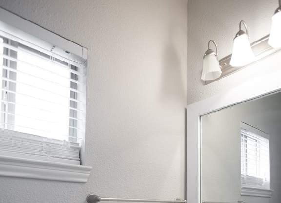 A white sink in a bathroom with a mirror and a window.