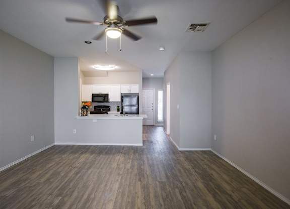 A room with a ceiling fan and wooden flooring.