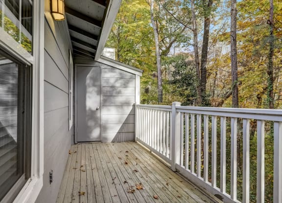 a deck with a view of the woods and a door to a storage closet at Veridian at Sandy Springs