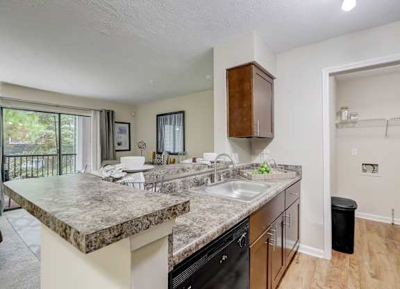 A kitchen with a marble countertop and black appliances.