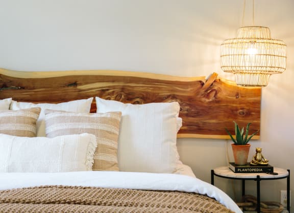 a bed with white pillows and a wooden headboard and two lamps at Tapestry at Hollingsworth Park