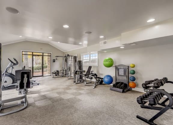 renovated gym with cardio equipment and weights and white walls with natural light