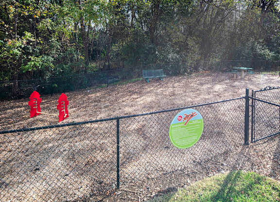 A fenced area with a sign and red objects in the distance.