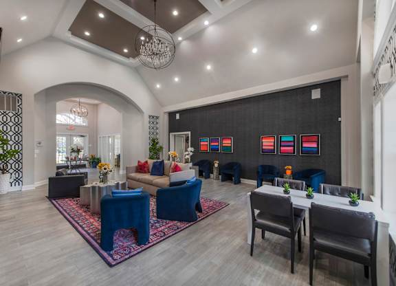 A spacious living room with a blue rug and a dining table set up.