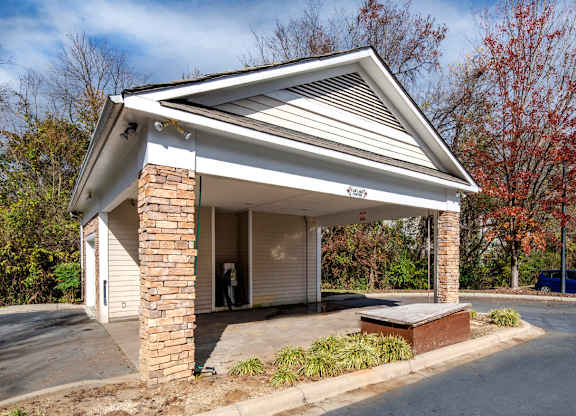 A small white building with a gabled roof and a brick pillar.