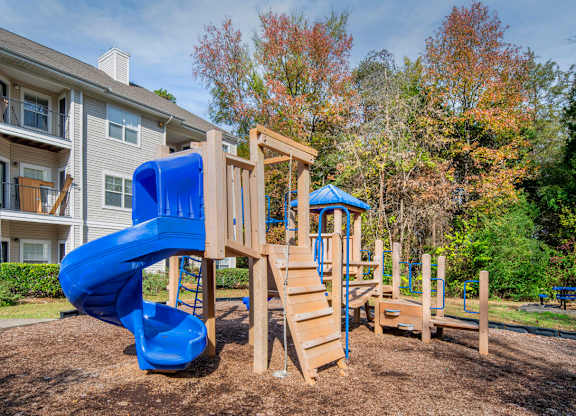 A playground with a blue slide and wooden structure.