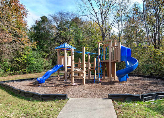 A playground with a blue slide and wooden structure.