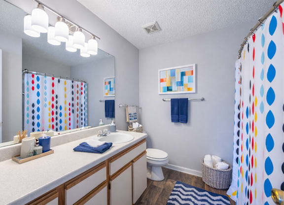 A bathroom with a white counter top and a mirror above it.