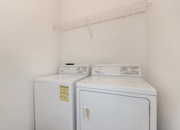 Two white washing machines in a small laundry room.