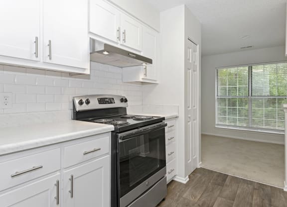 a kitchen with white cabinets and a stainless steel black stove top oven at Canopy at Baybrook apartments in Charlotte NC