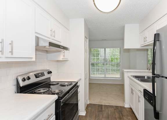 A kitchen with white cabinets and black appliances.