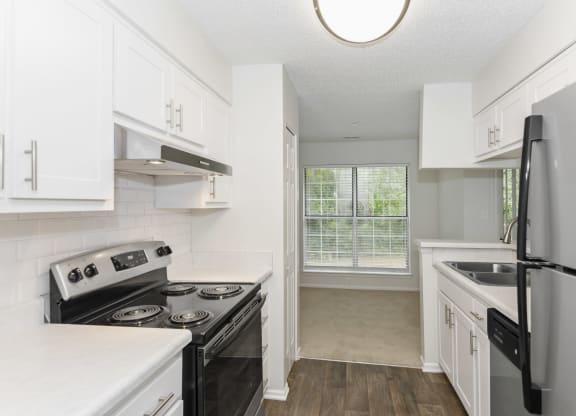 a kitchen with white cabinets and black stainless steel appliances at Canopy at Baybrook apartments in Charlotte NC