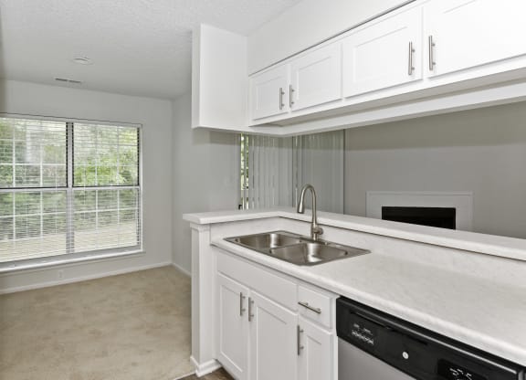 a kitchen with white cabinets and a large window at Canopy at Baybrook apartments in Charlotte NC