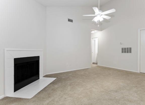a living room with a fireplace and a vaulted ceiling and fan at Canopy at Baybrook apartments in Charlotte NC