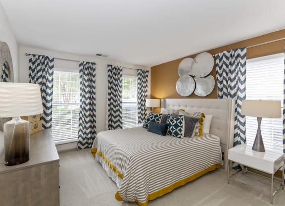 a bedroom with a large bed and a dresser with a lamp on it at Canopy apartments in South Charlotte