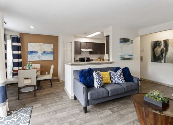 a living room with a couch a table and a kitchen in the background at Canopy at Baybrook apartments in South Charlotte