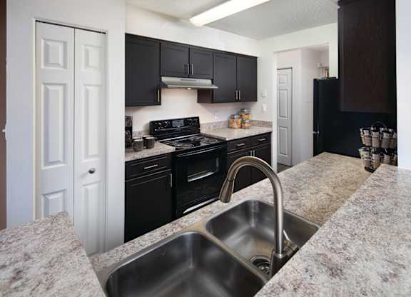 A kitchen with granite countertops and black cabinets.