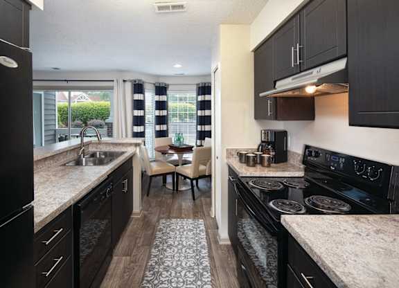 A kitchen with black cabinets and a granite countertop.