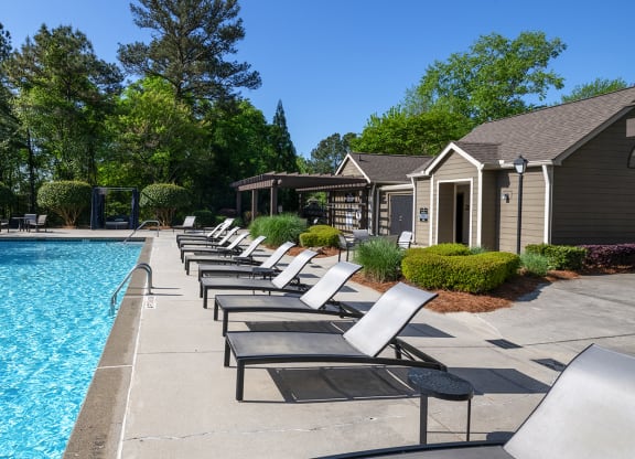Wynnwood Vinings resident swimming pool with chaise lounge chairs and trees in the background