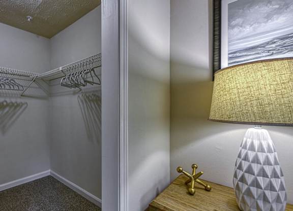 A lamp with a white shade and a gold base sits on a wooden table.