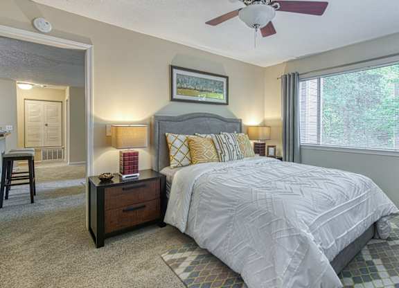 A bedroom with a bed, nightstand, and a ceiling fan.