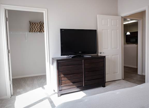 A black TV sits on a wooden cabinet in a room with white walls.