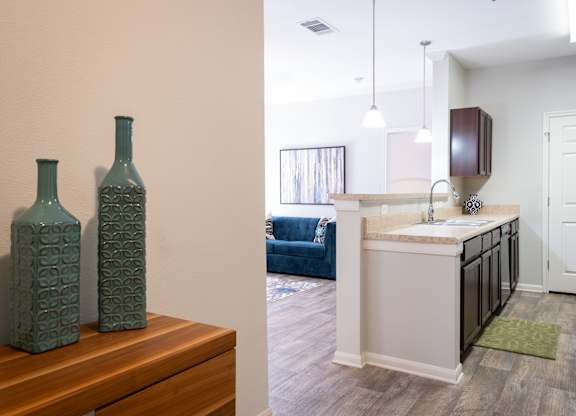 Two green bottles on a wooden table in a room with a blue couch.