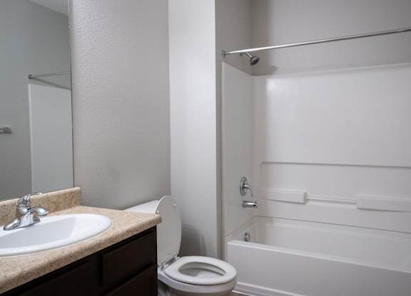 A white bathroom with a toilet, sink, and bathtub.