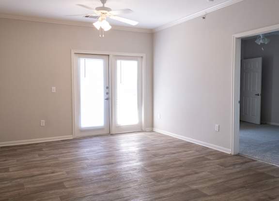 A room with a ceiling fan and sliding glass doors.