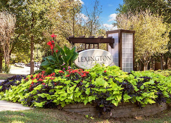 a sign in front of a garden of flowers