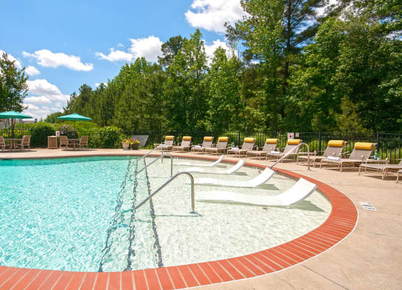 a swimming pool with chairs and umbrellas at Millennium Apartments Greenville SC