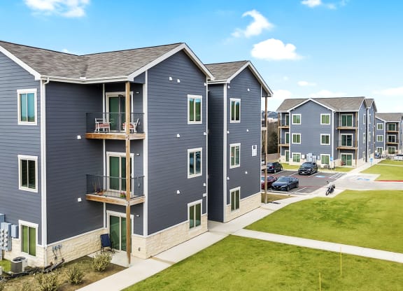 a row of apartments with blue roofs and green grass